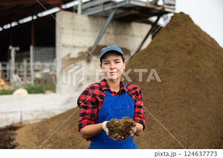 Female farmer with shovel poses against pile of dried and crushed cow dung in the backyard of farm Female farmer with shovel poses against pile of dried and crushed cow dung in the backyard of farm 124637773