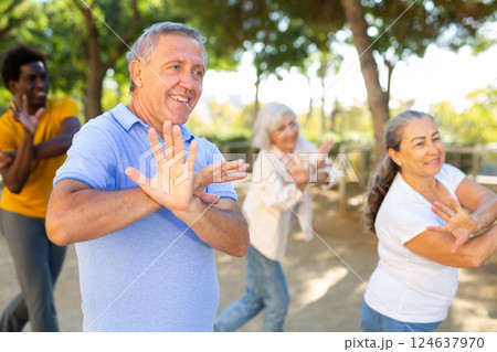 Carefree diverse people dancing rhythmic dance aerobic workout in park during spring day 124637970