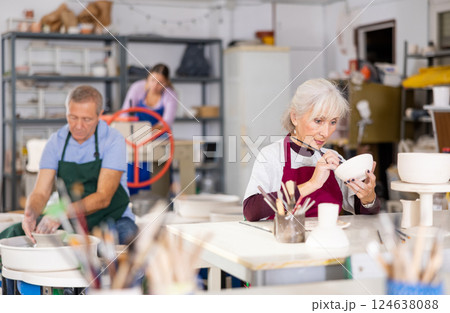Mature woman painting clay ceramic at art studio Mature woman painting clay ceramic at art studio 124638088
