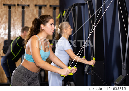 Girl exercising upper body muscles on ski machine in gym 124638216