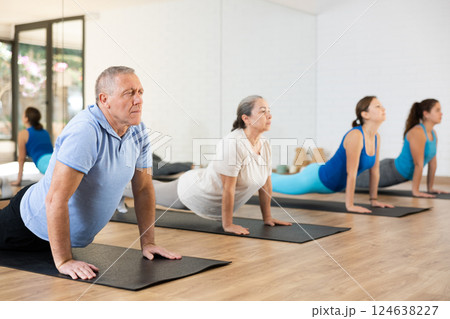 Old man practicing pilates on mat in gym area 124638227