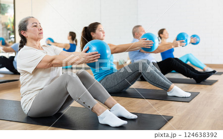 Elderly woman practicing pilates with ball in gym area 124638392