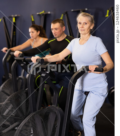 Group of people engaged in a spin bike simulator in the gym, exercising on stationary bike 124638460