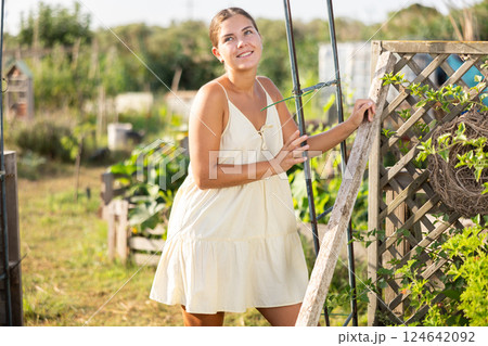Female peasant girl stands near garden bed, near chicken coop and enjoys country activities 124642092