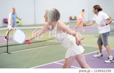 Mature woman playing doubles pickleball game, healthy lifestyle concept 124642290