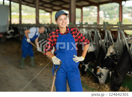 Portrait of successful girl farmer standing in open cowshed at dairy cow farm Portrait of successful girl farmer standing in open cowshed at dairy cow farm 124642301