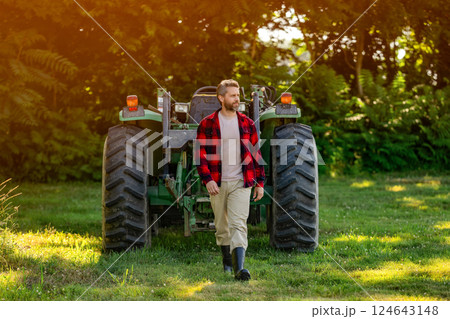 Mature man at tractor. Tractor driver. Agriculture and field work. Farmer in field wearing gum boot with tractor outdoor. Crop harvesting. Agriculture agrotechnology. Farmer with harvesting machinery 124643148