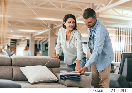 Big choice of colors and materials. Couple choosing the sofa and bed in the store 124643910