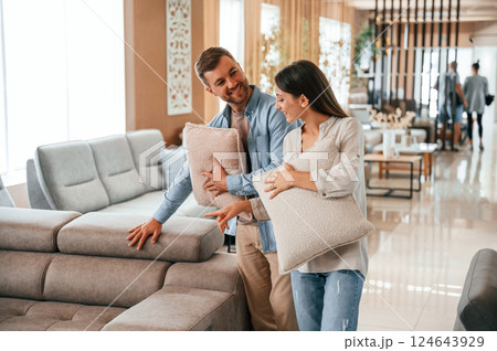 Beautiful product. Couple choosing the sofa and bed in the store 124643929
