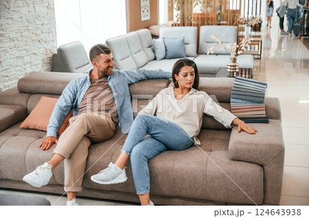 Sitting and relaxing. Couple choosing the sofa and bed in the store 124643938