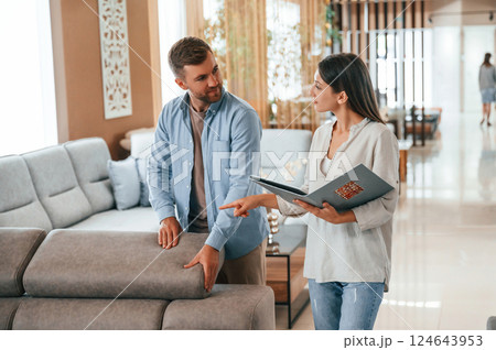 Talking with each other. Couple choosing the sofa and bed in the store Talking with each other. Couple choosing the sofa and bed in the store 124643953