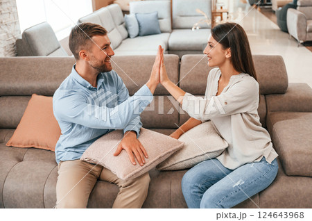 Smooth material. Couple choosing the sofa and bed in the store 124643968