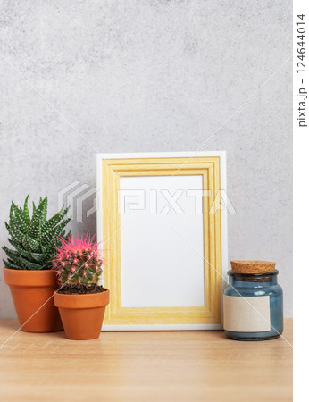 Empty photo frame with cacti, candle and copy space on wooden table 124644014
