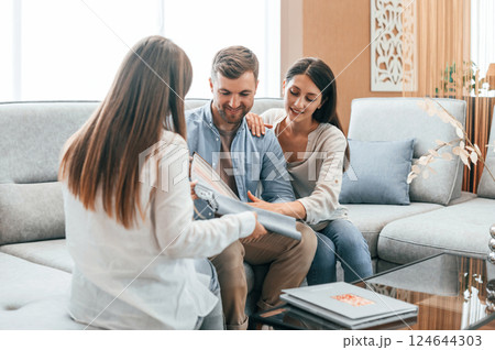 Sitting together. Woman helping couple with choosing the sofa and bed in the store 124644303