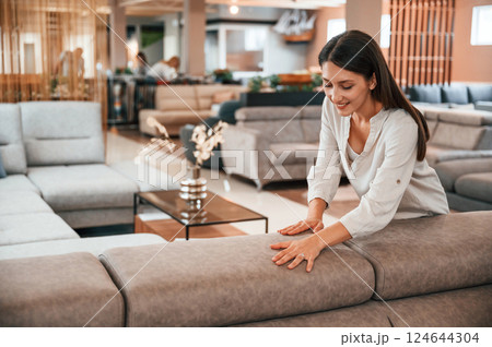 Touching the smooth surface. Woman is visiting bed store. Looking for comfortable sofa 124644304