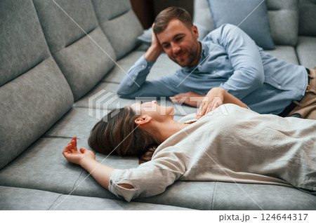 Side view. Laying down together. Couple choosing the sofa and bed in the store 124644317