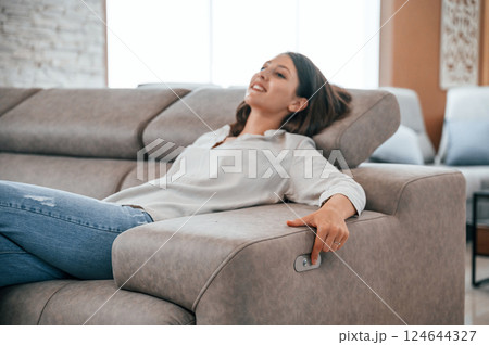 Trying automatic switches. Woman is visiting bed store. Looking for comfortable sofa Trying automatic switches. Woman is visiting bed store. Looking for comfortable sofa 124644327