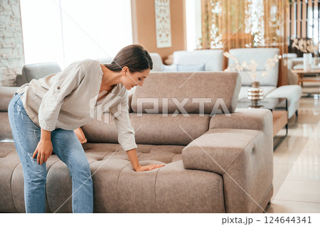 Sitting and relaxing. Woman is visiting bed store. Looking for comfortable sofa 124644341