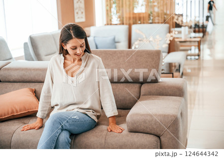 Sitting and relaxing. Woman is visiting bed store. Looking for comfortable sofa 124644342