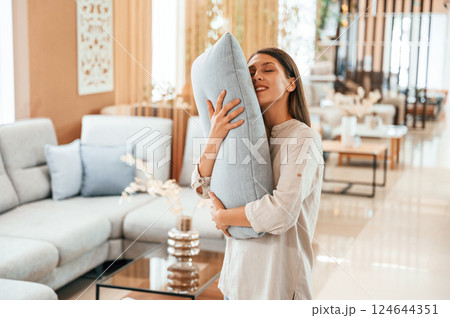 Embracing the pillow. Woman is visiting bed store. Looking for comfortable sofa 124644351