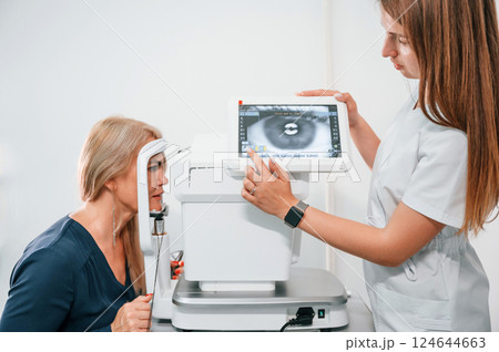Eye is on the monitor. Woman's vision is tested by clinic worker that using special device 124644663