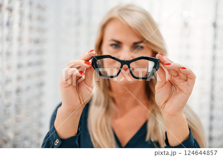 Holding glasses in hands. Woman is in the store 124644857