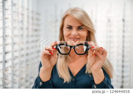 Holding glasses in hands. Woman is in the store 124644858