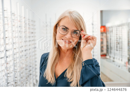 Looking at the camera. Woman in store trying new glasses Looking at the camera. Woman in store trying new glasses 124644876