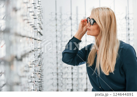 Woman in store trying new glasses Woman in store trying new glasses 124644891