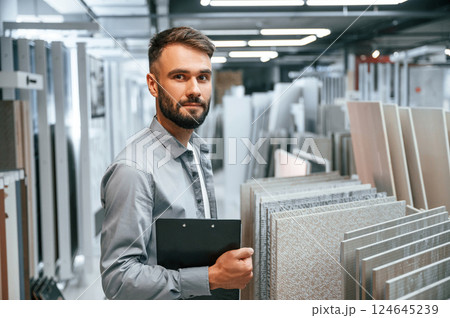 Standing with notepad in hands. Stylish beautiul man is in the store of goods for the home 124645239