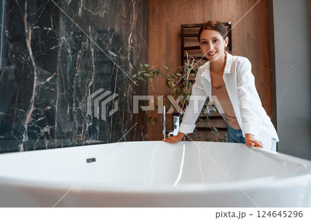 Leaning on the bath. Pretty young woman is in the store of goods for the home Leaning on the bath. Pretty young woman is in the store of goods for the home 124645296