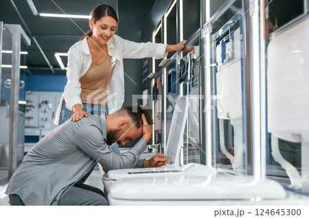 Man pretending he's feeling bad at the toilet. Woman and man is in the store of goods for the home 124645300