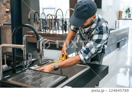 Works with sink. Plumber in uniform is indoors at home Works with sink. Plumber in uniform is indoors at home 124645789