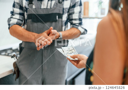 Close up view. Plumber receiving cash for the work he is done on the kitchen Close up view. Plumber receiving cash for the work he is done on the kitchen 124645826