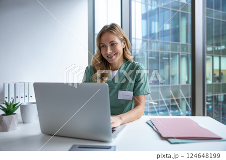 Woman doctor in hospital working with computer preparing medical documents Woman doctor in hospital working with computer preparing medical documents 124648199