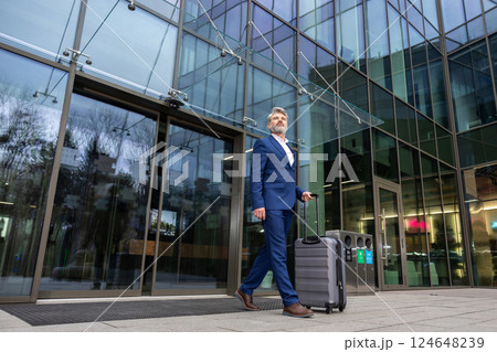 Elegant man in blue suit carrying a suitcase 124648239