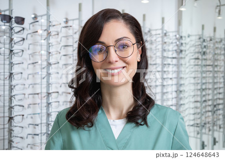 Pretty young dark-haired woman at the glasses stand in the optic shop Pretty young dark-haired woman at the glasses stand in the optic shop 124648643
