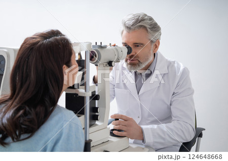 Male optician testing woman sight and providing eye consultation Male optician testing woman sight and providing eye consultation 124648668