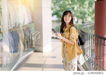 Traveler young asian woman 30s using smartphone while exploring urban street in Bangkok, Thailand. Traveler young asian woman 30s using smartphone while exploring urban street in Bangkok, Thailand. 124648903