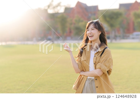Traveler asian woman in her 30s stands bathed in the golden glow of sunset, embracing the freedom of exploration. on summer holiday weekend vacation trip in Bangkok, Thailand 124648928
