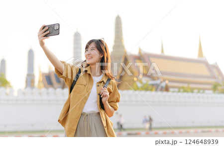 Traveler asian woman in her 30s explores the Grand Palace with a local guide. Uncover hidden gems and immerse yourself in Thai culture with her adventure. Traveler asian woman in her 30s explores the Grand Palace with a local guide. Uncover hidden gems and immerse yourself in Thai culture with her adventure. 124648939