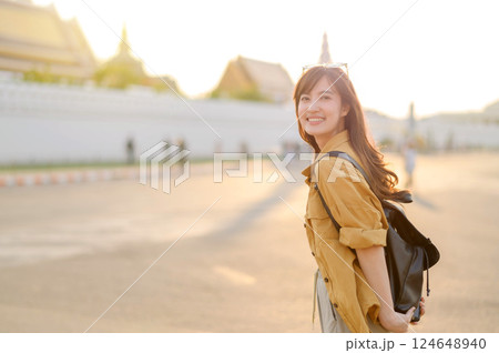 Traveler asian woman in her 30s stands bathed in the golden glow of sunset, embracing the freedom of exploration. on summer holiday weekend vacation trip in Bangkok, Thailand 124648940