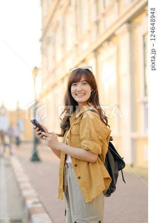 Traveler asian woman in her 30s using smartphone for navigation destination on the urban street at Bangkok, Thailand. Traveler asian woman in her 30s using smartphone for navigation destination on the urban street at Bangkok, Thailand. 124648948