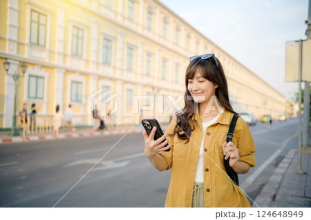 Traveler asian woman in her 30s using smartphone for navigation destination on the urban street at Bangkok, Thailand. Traveler asian woman in her 30s using smartphone for navigation destination on the urban street at Bangkok, Thailand. 124648949