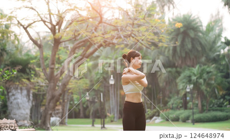 Shoulder pain problem. woman jogger. 30s asian female wearing white sportswear holding her shoulder with pain after running exercise in public park. Shoulder pain problem. woman jogger. 30s asian female wearing white sportswear holding her shoulder with pain after running exercise in public park. 124648974