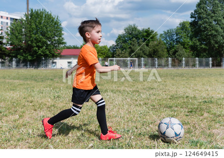 Young boy running towards soccer ball outdoors. 124649415
