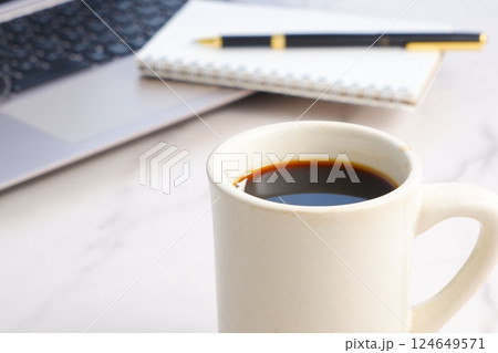 コーヒーを飲みながら、ノートパソコンでデスクワークをしているイメージ写真 コーヒーを飲みながら、ノートパソコンでデスクワークをしているイメージ写真 124649571