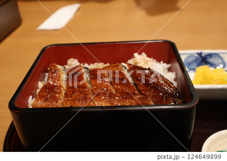 テーブルの上のごはんに鰻のかば焼きののったうな重が入った器にピント合わせ撮影した風景 テーブルの上のごはんに鰻のかば焼きののったうな重が入った器にピント合わせ撮影した風景 124649899