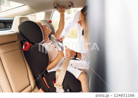 Girl is in a special baby seat. Young woman with her little daughter is with their electric car outdoors 124651166
