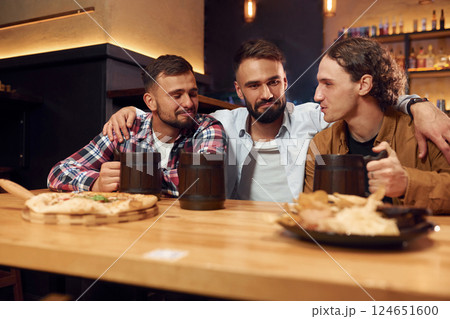 Having a conversation. Three friends are in the bar drinking beer and having a good time 124651600